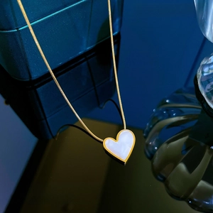 Macro detail of heart-shaped mother of pearl pendant on 18K gold plated necklace