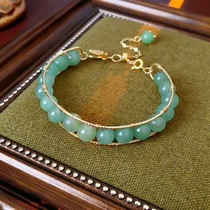 Detailed shot of green tiger eye beads with gold wire wrapping and leaf pendant charm