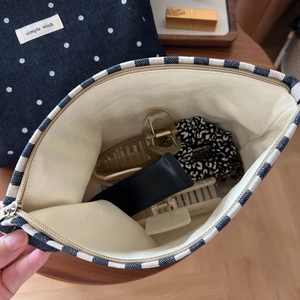 Interior view of stripe canvas makeup bag showing storage capacity for hair accessories