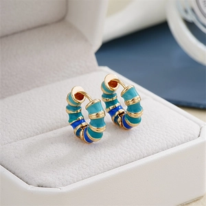 Detailed macro view of bamboo-shaped enamel hoop earrings in blue and gold colors