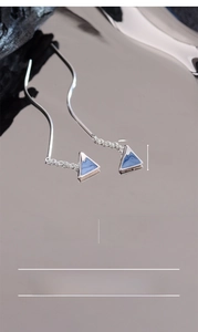 Macro shot of silver-plated mountain triangle earrings with blue enamel finish