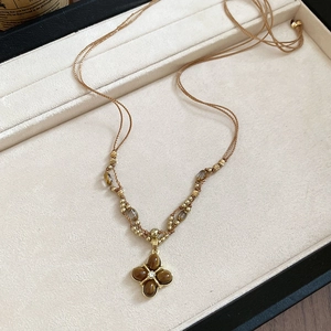 Detail of tiger eye flower pendant necklace with beads on brown braided cord strap
