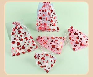 Close-up of five sheer organza gift bags featuring red foil hearts and silk drawstrings