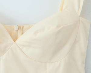 Detailed view of beige sleeveless dress with heart neckline and concealed zipper closure