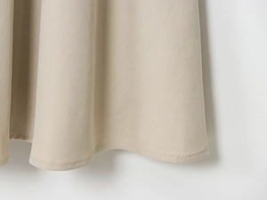 Détail de l'ourlet de robe kaki avec double surpiqûre précise et texture de tissu tissé