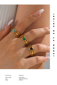 Detail of three gold hollow rings with blue green and black stone inlays on fingers