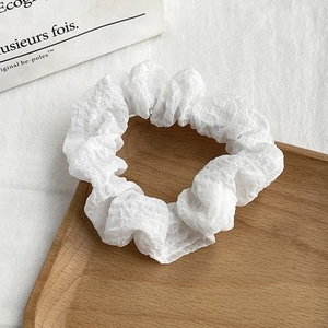 Elegant white floral scrunchie with wrinkled texture on a rustic wooden tray decor