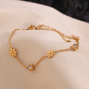 Macro shot of 18K gold plated bracelet featuring flower motifs and sparkling rhinestones