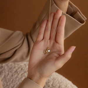 Collier cœur doré avec lettre A et pierre de naissance tenu dans la main