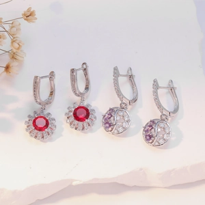 Elegant silver U-shape earrings with red and purple gemstones on white stone base