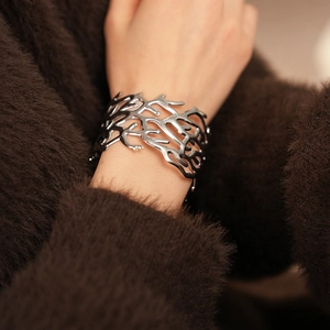 Close-up of a silver molten lava style open cuff bracelet on a sweater sleeve