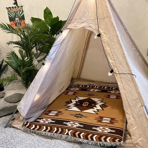 Bohemian style camping blanket inside a beige pyramid tent with ethnic patterns