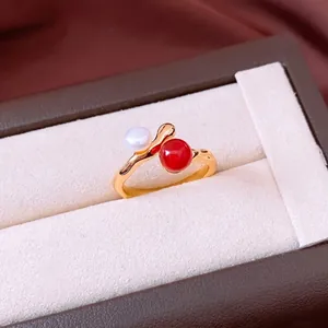 Vergoldeter Ring mit weißer Perle und roter Perle auf luxuriöser Schmuckschatulle