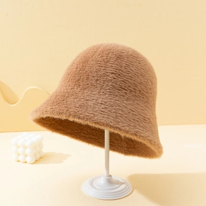 Detail view of camel faux mink fur bucket hat on a minimalist display stand with warm decor