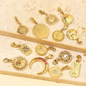 Golden bohemian pendants with sun moon and star motifs on a textured stone background
