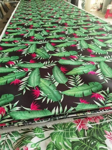 Detail of tropical plant pattern with green leaves and pink flowers on black canvas fabric
