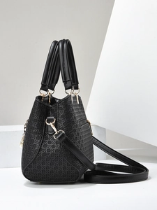 Detailed view of black woven texture leather handbag with adjustable gold-tone metal hardware
