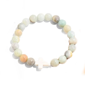 Handmade beaded bracelet with turquoise stones and a white cross pendant on white background