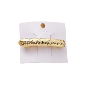 Golden round hair clip with hammered texture on a display card for women