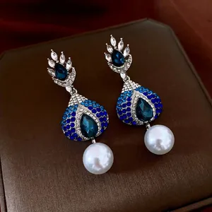Elegant silver earrings with blue crystals and large white pearl teardrops on leather box