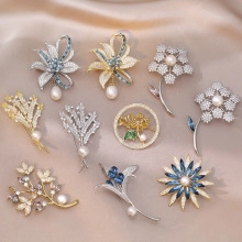 Detailed flat lay of floral crystal brooches with pearls on champagne silk background