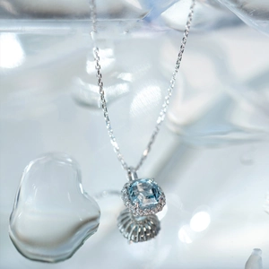 Macro shot of square-cut aquamarine pendant with sparkling diamond halo on silver chain