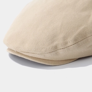 Detailed close-up of camel cotton beret fabric with white double-line stitching