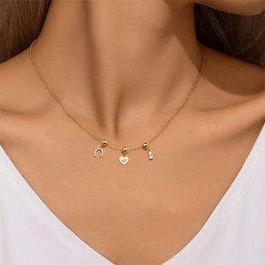 Detailed close-up of a golden horseshoe and heart zircon necklace on a model's neck