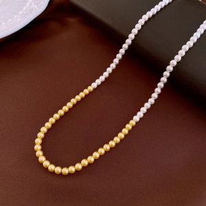 Detail of dual-tone French vintage necklace with white and gold circular pearls