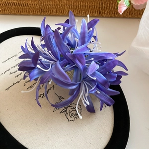 Vue détaillée d'une pince à cheveux fleur de lys en tissu bleu dégradé sur socle rétro