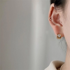 Close-up of gold heart zircon earrings and crescent moon studs on a model's ear