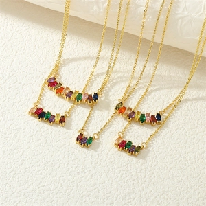 Close-up of four gold necklaces with multi-color marquise-cut gemstones on white texture