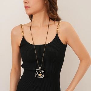 Détail d'un pendentif carré mat avec cœur doré sur une chaîne à deux couches stylée