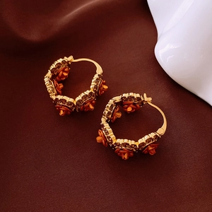 Détail de boucles d'oreilles dorées en U avec rose orange et cristaux bruns brillants
