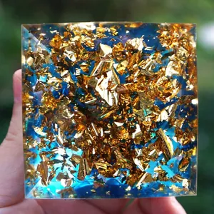 Handheld Orgone pyramid featuring gold foil and blue crystal stones in clear resin