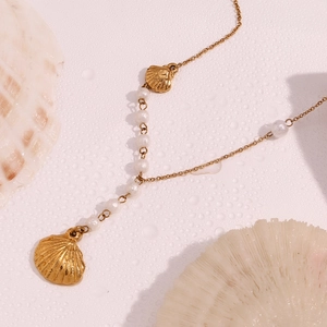 Detailed view of 18K gold plated necklace with shell pendant and white faux pearls