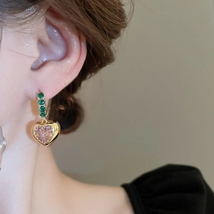 Close-up of vintage gold heart earring with green square gem and pink zircon pendant