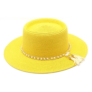 Détail d'un chapeau de paille jaune avec chaîne dorée, perles et glands blancs