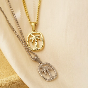 Collane con ciondolo a palma hawaiana in oro e argento su elegante sfondo di raso
