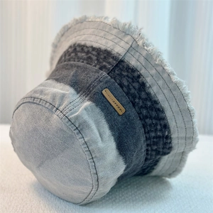 Detail of gradient denim bucket hat featuring frayed edges and a metal logo plate