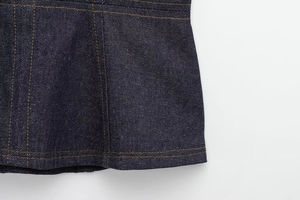 Macro shot of dark blue denim hem with contrast orange topstitching and twill texture
