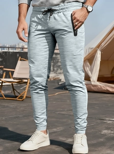 Detail of men's athletic joggers featuring drawstring waist and textured grey fabric