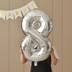 Silver number 8 foil balloon detail held against a cream wall with a Happy banner