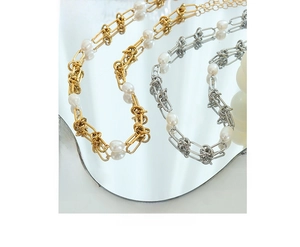 Detail of gold and silver plated twist chain necklaces with pearls on a mirror