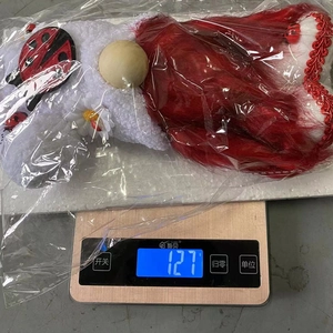 Detail view of a 127g Christmas gnome plush toy on a digital weight scale in a package