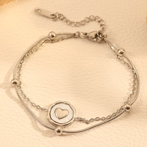 Close-up of double-layered silver titanium steel bracelet with heart pendant and beads