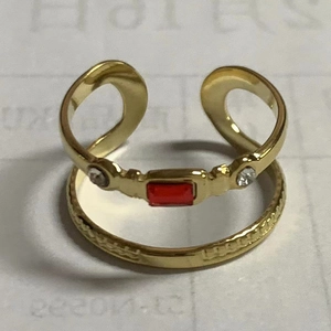 Detailed close-up of golden geometric ring set with a central red stone and small gems