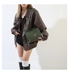 Detail of dark green leather shoulder bag with floral embossing and bronze metal clasp