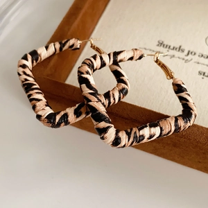 Close-up of leopard print fabric textures on square hoop earrings with golden studs