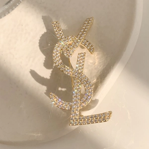 Detailed view of a gold-plated bow brooch with sparkling cubic zirconia and pearl tassel